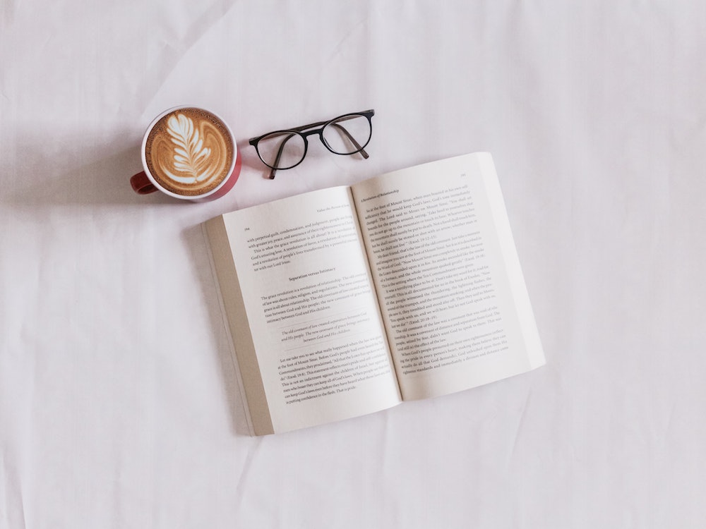 A book next to some glasses and fancy coffee.